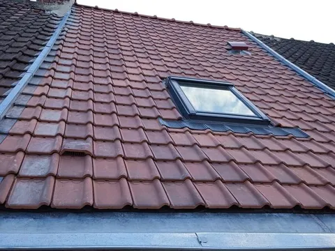 Couverture en tuiles rouges neuves avec fenêtre de toit Velux installée